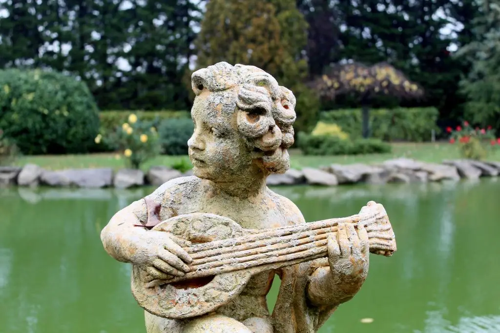 Ancient stone sculpture of a musician in an İstanbul garden reflecting musical history.